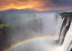 Gorgeous view of Victoria Falls at sunset with a rainbow forming in the mist, Zambia, Africa